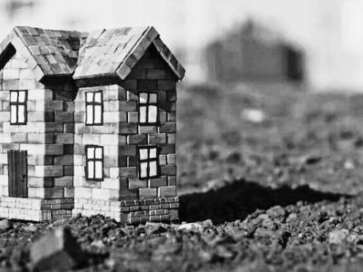 The image showcases a miniature building on some dirt land.