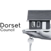Image shows the Dorset Council Logo alongside a small miniature property held in a hand with a set of keys.