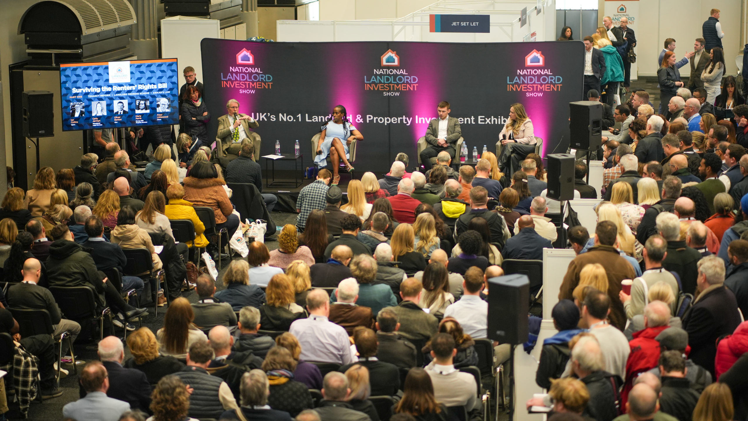 Panel discussion with 4 people on a panel answering questions from a large seated auidence.