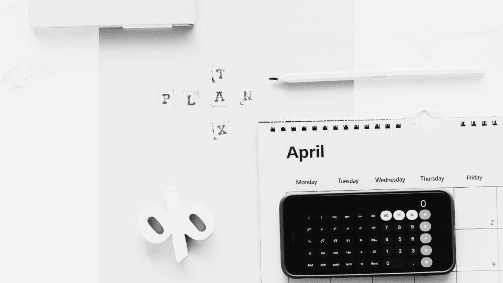 Black and white image of an Iphone calculator and folder stating tax plan.