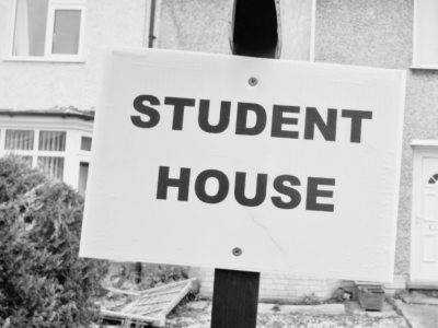 Black and white image of board outside residential house stating Student House