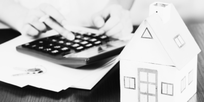 Black and white image of house and calculator with files