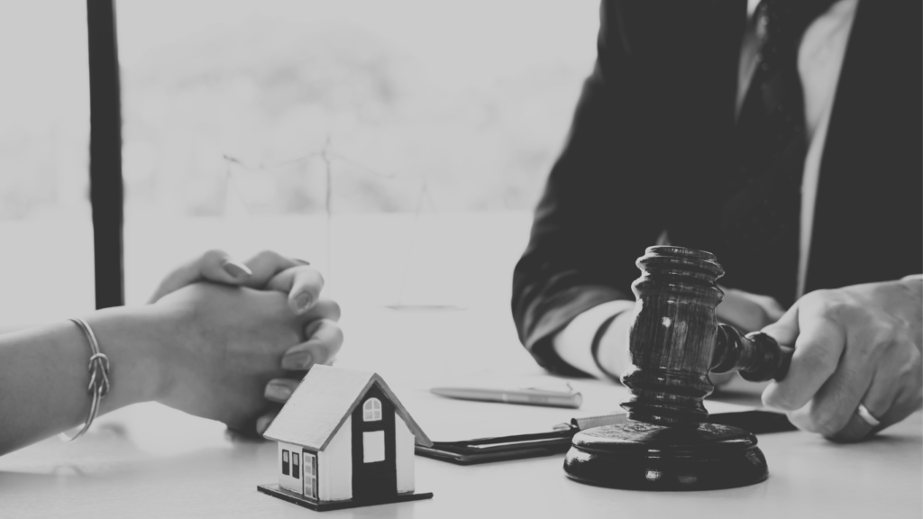 Black and white image of auction hammer and house.