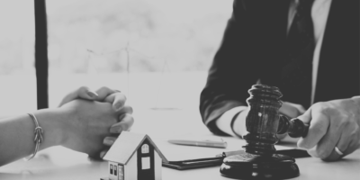 Black and white image of auction hammer and house.