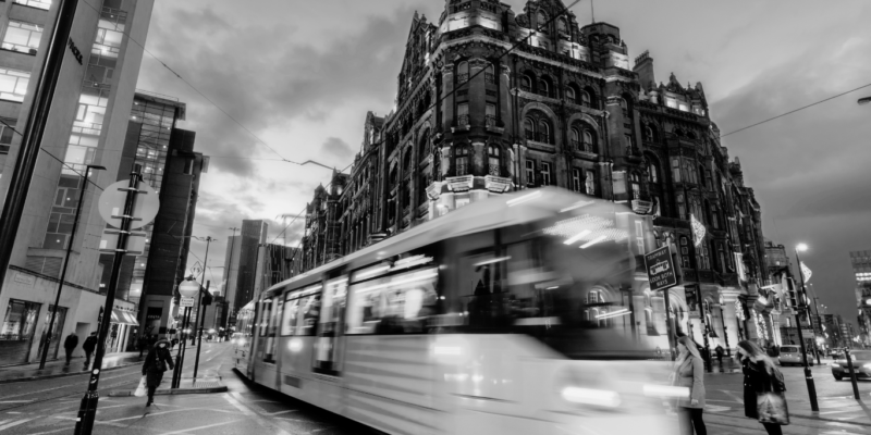 Black and white image of Manchester city centre with tram