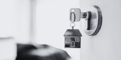 Black and white door open with metal house keyring and key in latch.
