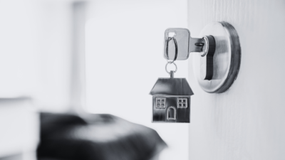 Black and white door open with metal house keyring and key in latch.