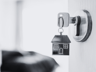 Black and white door open with metal house keyring and key in latch.
