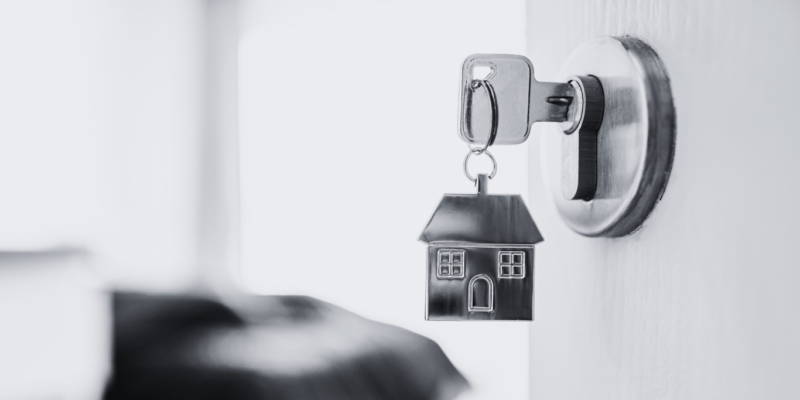 Black and white door open with metal house keyring and key in latch.