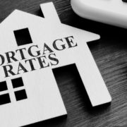 Mortgage Rates Text over cut out wooden house with pen to the right of the image