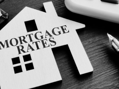 Mortgage Rates Text over cut out wooden house with pen to the right of the image