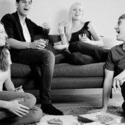 Black and white image of shared living space and 4 people with 2 sitting on the coach.