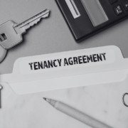 Tenancy agreement file with a keyring of a house in black and white and paper pins