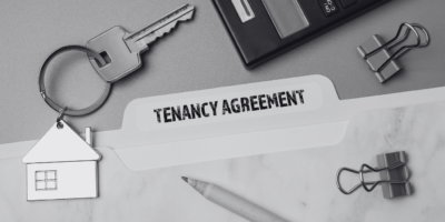 Tenancy agreement file with a keyring of a house in black and white and paper pins