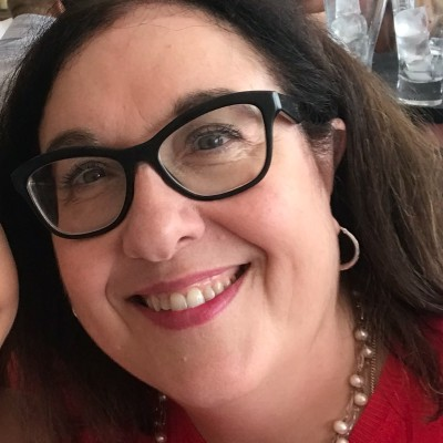 Selfie image of woman with dark brown hair and black glasses smiling 