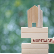 Building blocks with house on top and jenga wooden piece stating mortgage