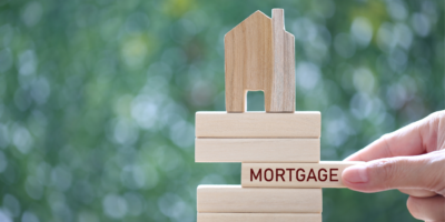 Building blocks with house on top and jenga wooden piece stating mortgage