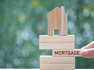 Building blocks with house on top and jenga wooden piece stating mortgage