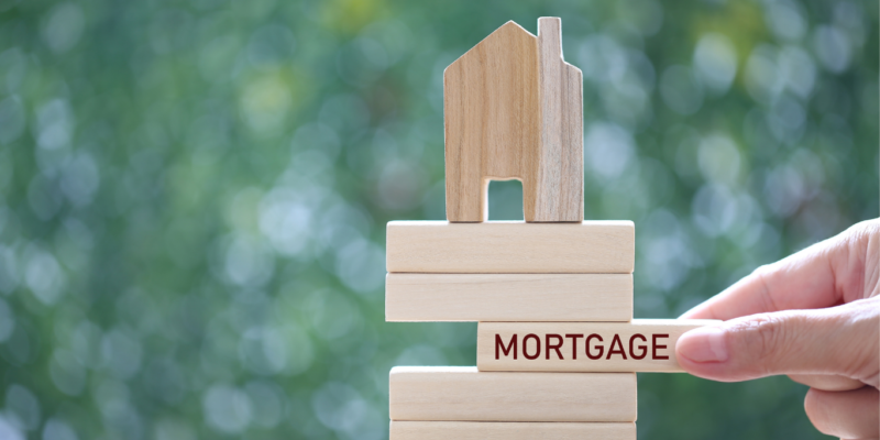 Building blocks with house on top and jenga wooden piece stating mortgage