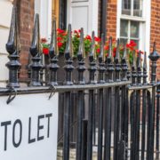 Railings outside proeprty with flowers and 'To let' signage in black text.