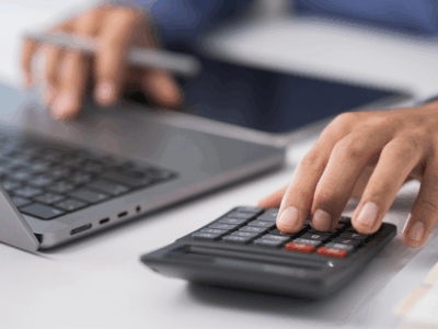 A man's hands typing and hand on a calculator