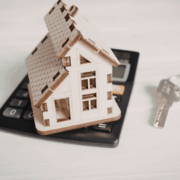 House model on top on calculator by a set of silver keys with a house keyring