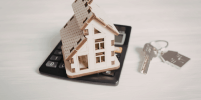 House model on top on calculator by a set of silver keys with a house keyring