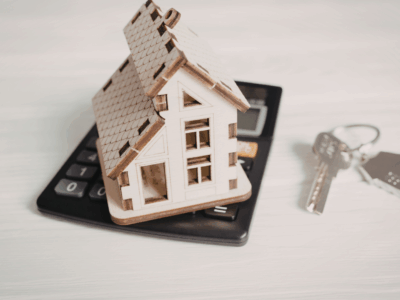 House model on top on calculator by a set of silver keys with a house keyring