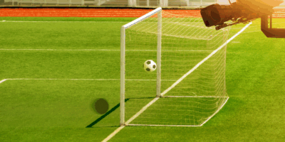 Football pitch with ball in the goal and a camera overlooking this