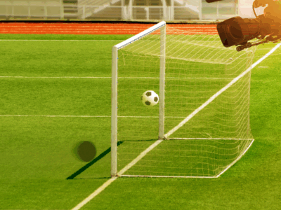 Football pitch with ball in the goal and a camera overlooking this