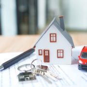 House model with red car, keys sitting on top of paperwork