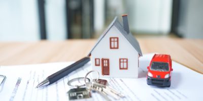 House model with red car, keys sitting on top of paperwork