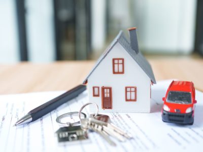House model with red car, keys sitting on top of paperwork