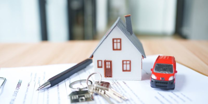 House model with red car, keys sitting on top of paperwork