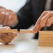 Picture with wooden blocks and a male hand bridging the wooden blocks together