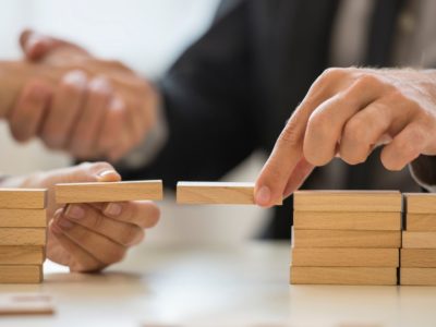 Picture with wooden blocks and a male hand bridging the wooden blocks together