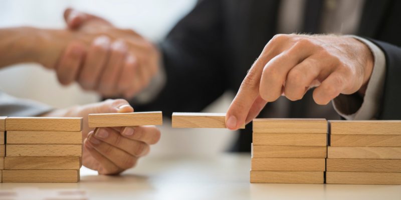 Picture with wooden blocks and a male hand bridging the wooden blocks together